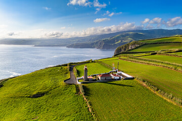 Lighthouse on Cape Cintrao surrounded by lush green pastureland, Azores Aerial view © Leonid