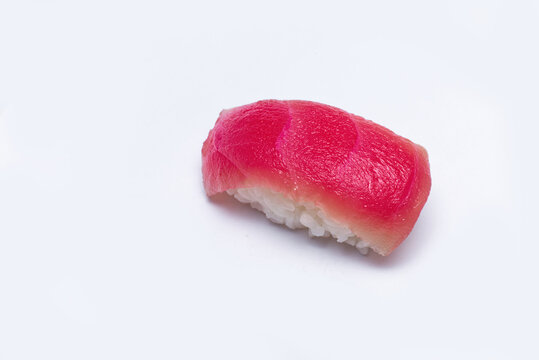Single piece of fresh tuna nigiri sushi (Maguro) isolated on a white background, featuring a vibrant red slice of raw fish over seasoned rice