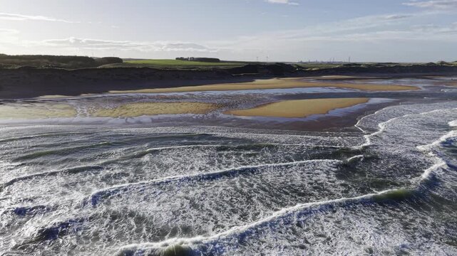 Cinematic aerial waves washing onto sandy coastline