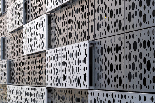 Modern architecture abstract facade where perforation pattern and metal texture create geometry across a refined graphic surface revealing detail