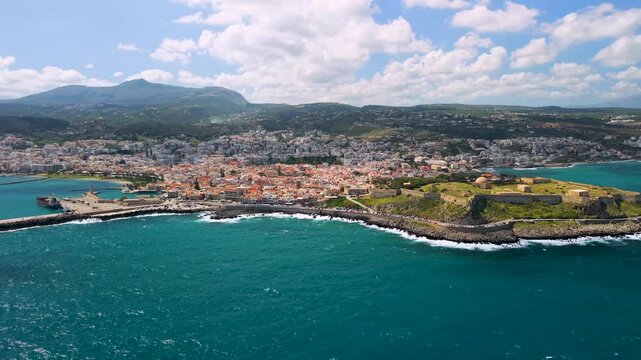Rethymno Crete Greece aerial panorama of Venetian Fortezza castle and old town, drone panning view of city port and coastline, Mediterranean seascape from sea at sunset for travel video
