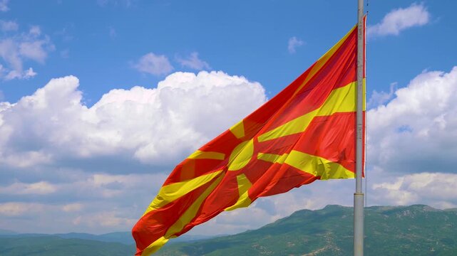 Macedonia flag on flagpole waving on wind. Slow Motion Macedonia Flag Waving Macedonian Flag Flying. Macedonian flag flying high on pole against blue sky background on clear day. North Macedonia