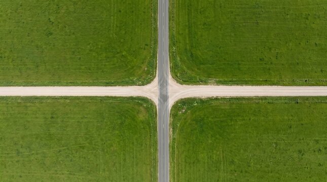 Aerial top down rural road intersection in green fields