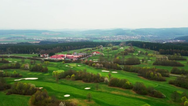 Dynamische 4K-Luftaufnahme eines Golfplatzes: Eleganter Dolly-Pan &uuml;ber gr&uuml;ne Fairways und Sandbunker.