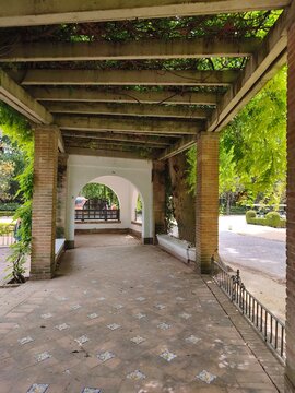 Historic pergola corridor with arches and ceramic tiles in Parque Maria Luisa, Seville, Spain