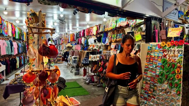 A woman explores a colorful souvenir market in Poblacion V, Philippines, in smooth slow motion.