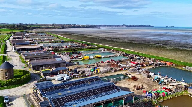 Drone shot of a Cancale oyster operation with solar panels and basins beside a tidal bay.France, Cancale