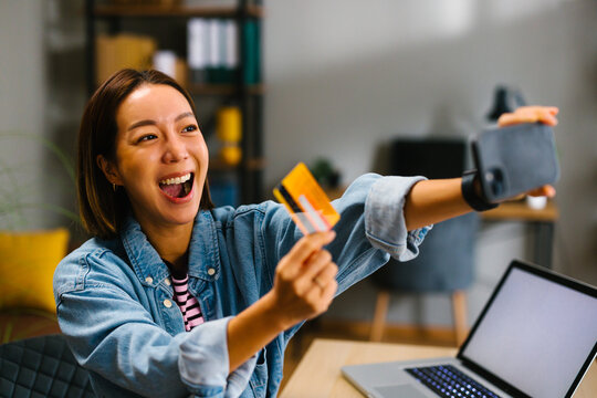 Young woman making online payment with credit card and smartphone at home
