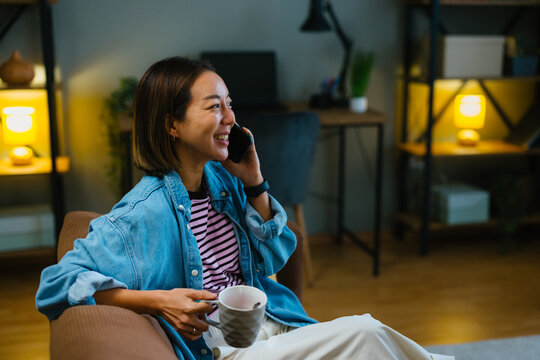 Young woman enjoying phone call conversation while relaxing at home