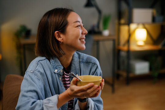 Smiling woman holding bowl of oatmeal and looking away