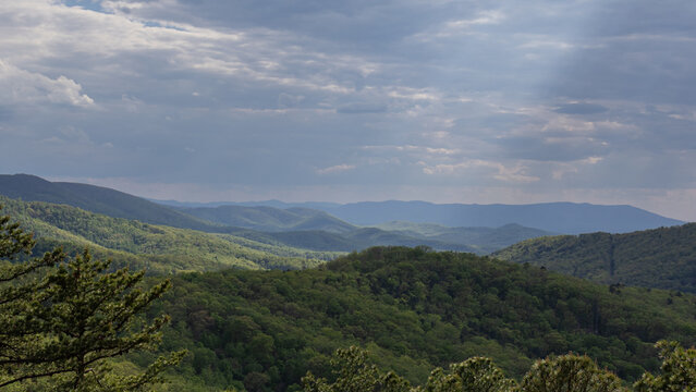 Rolling Mountain Landscape with Forested Ridges and Dramatic Cloudy Sky