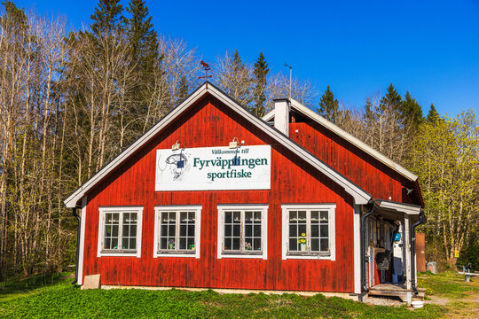 Close up view of Scandinavian fishing base wooden house with red facade and white windows on background of forest. Sweden. 