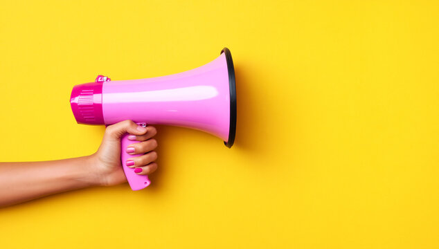 hand holding bright pink megaphone against vibrant yellow background for communication and promotion