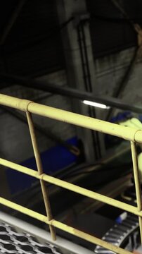 In a dimly lit factory, a robotic arm is positioned above a conveyor belt, showcasing precision and efficiency in automation. This scene reveals the future of manufacturing.