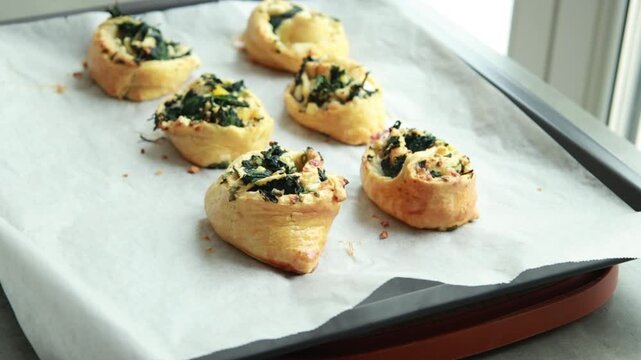 Freshly baked golden puff pastry appetizers with spinach and cheese on a baking tray