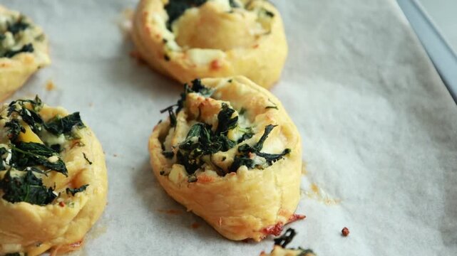 Freshly baked golden puff pastry appetizers with spinach and cheese on a baking tray