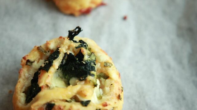 Freshly baked golden puff pastry appetizers with spinach and cheese on a baking tray