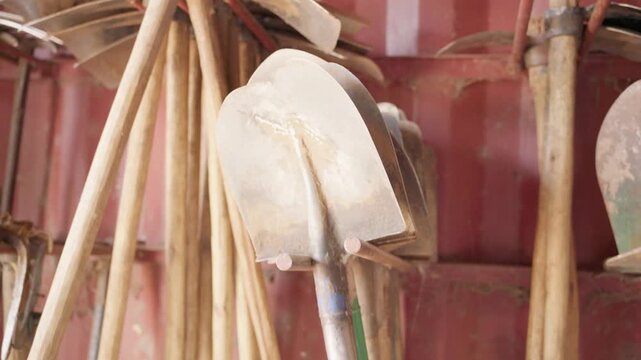 Row of metal shovels stored in an agricultural tool shed