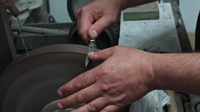 Professional Knife Sharpening in 4K Slow Motion &ndash; Close-Up of Craftsman Honing Folding Knife Blade on Rotating Sharpening Stone, Precision Blade Maintenance Workshop