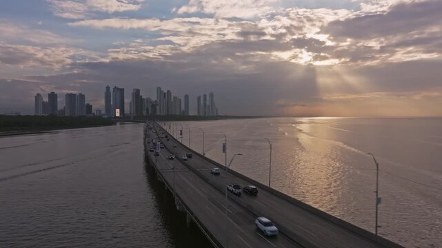 Aerial drone shot looking at the sun's rays during sunrise, flying forward over the maritime section of the Corredor Sur in Panama City