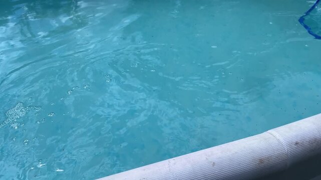 Horizontal Close up of the hands cleaning a swimming pool with a special pool cleaning net. side view