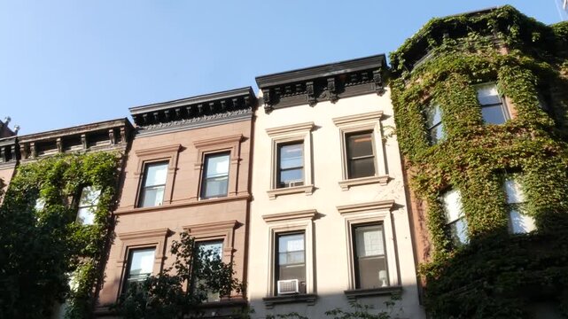 New York City townhouse buildings, brownstone row houses in Manhattan or Brooklyn, United States of America. Classic buildings on residential district street. Real estate property. Rowhouse townhome.