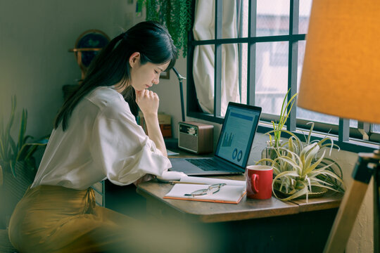 自宅でノートパソコンを前に落ち込む若い日本人女性