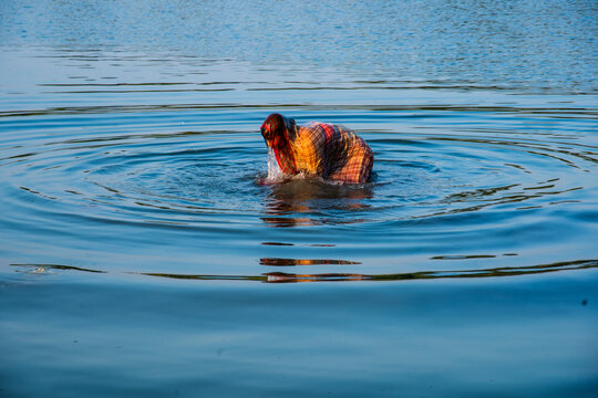 Traditionally dressed Indian woman pray into the river on Chhat Puja Festival.