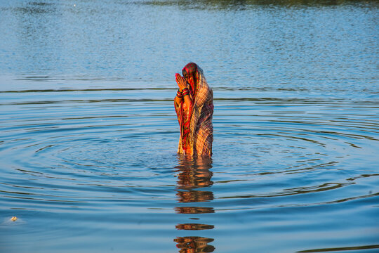 Traditionally dressed Indian woman pray into the river on Chhat Puja Festival.