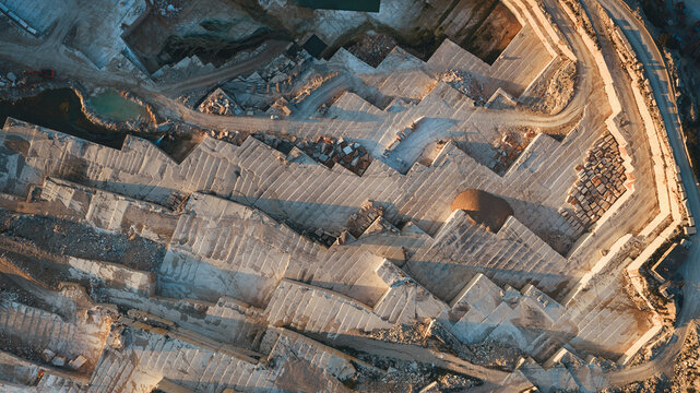 Aerial view of Jadrankamen stone quarry with terraced limestone layers and industrial tracks in warm sunset light in Pucisca, Splitsko-dalmatinska, Croatia.