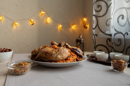moody still life of chicken kabsa with raisins, almonds, finjan cups and warm ramadan lights, suited to halal menu design, saudi cuisine themes and festive iftar visuals