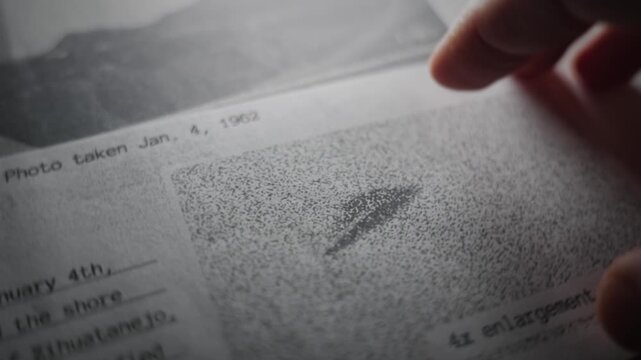 Retro looking government report close up of hand pointing at grainy photo of UFO. Classified top secret exposed information of alien extraterrestrial activity and sightings investigation in Area 51