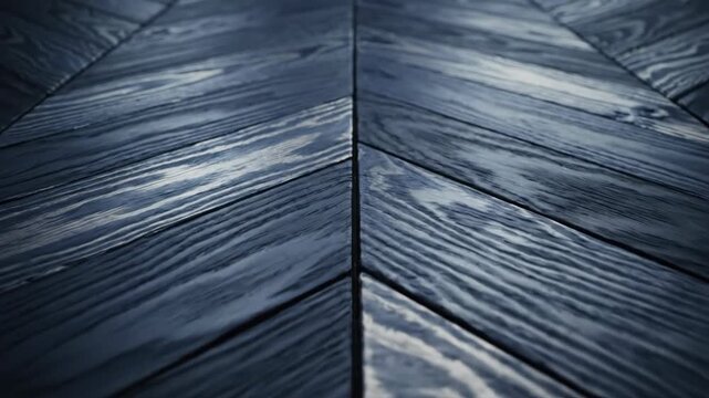 dark grey wooden floor laid in elegant chevron pattern. smooth polished surface with visible natural grain reflecting cool light. interior design element, architectural background, modern texture.
