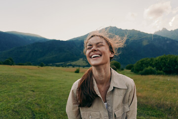 Happy woman enjoying outdoor life, smiling in a grassy field with mountains in the background, casual jacket, sunlit moment, lifestyle portrait of carefree everyday joy © SHOTPRIME STUDIO