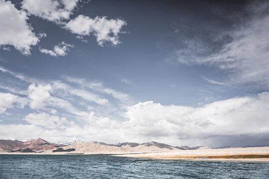 Mountain landscape, a cold high-altitude lake against the backdrop of rocky peaks and ridges with snow and glaciers, a panorama in the Tien Shan Mountains in the Pamirs, a lake with waves