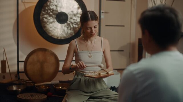 Sound healer tapping singing bowl during wellness therapy session