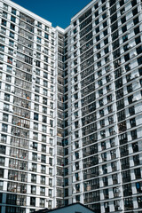 Fototapeta premium A tall residential building stands prominently in an urban environment, characterized by numerous balconies and clear glass windows