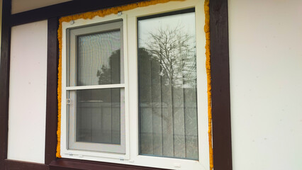 Naklejka premium The window shows a yellow trim with clear glass reflecting trees outside.