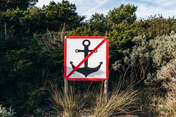 Prohibition sign with crossed anchor symbol indicating no anchoring zone on Ile de Porquerolles surrounded by Mediterranean vegetation © Andrei Antipov