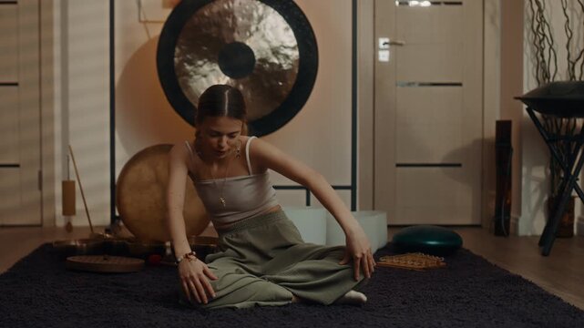 Woman stretching sideways in seated yoga pose with gong