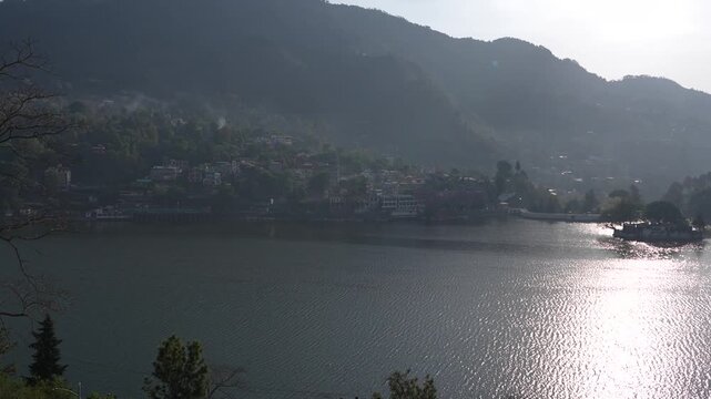 Broad lake view shows hills, houses, and clear sky with calm surroundings