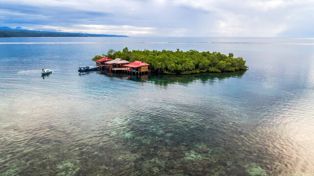 Boats moored by wooden buildings on a tropical island, Tumbak Bentenan Marine Park, Minahasa, North Sulawesi, Indonesia