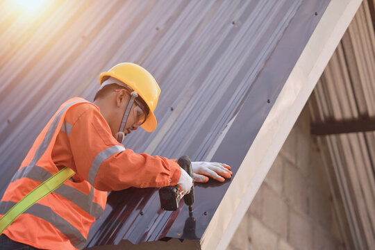 Side view of a Construction worker installing metal sheets on a roof, Thailand