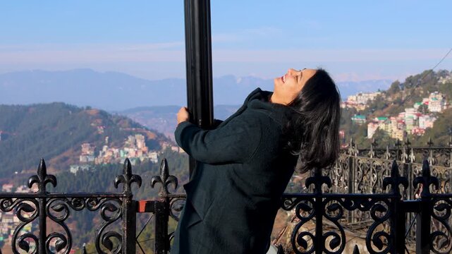 young woman enjoying scenic mountain view in shimla holding pole at viewpoint smiling outdoors