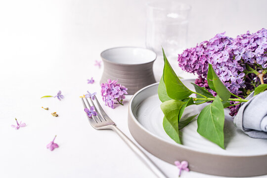 Close-up of a rustic spring place setting on a table with fresh lilac flowers