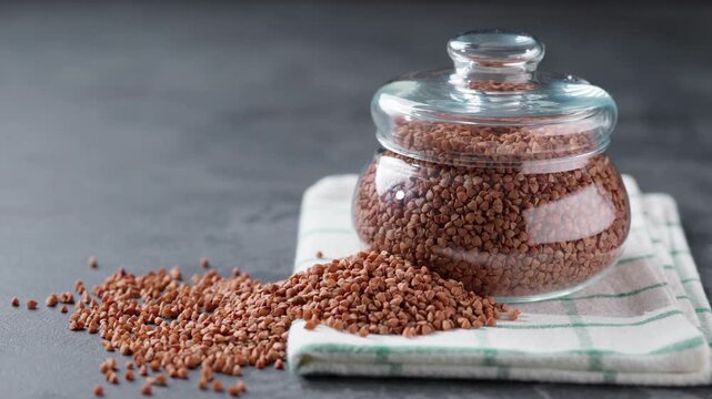 Organic buckwheat in glass storage jar on a dark table. buckwheat in a storage glass jar on a dark stone table.