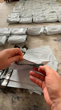 Moscow, Russia, 03.05.2026 Woman packing small goods into courier mailing bags for shipment. Online entrepreneur preparing parcels for delivery. Small business logistics and storage process.