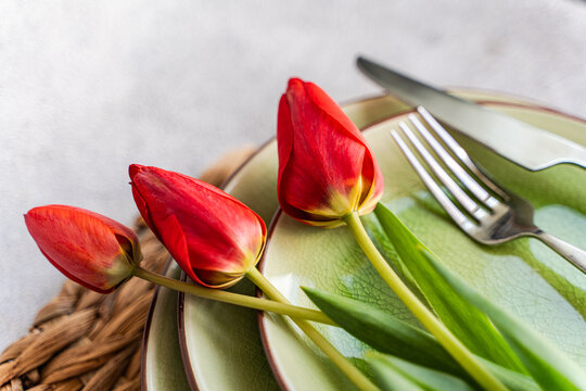 Close-up of a rustic Spring place setting on a table with red tulips