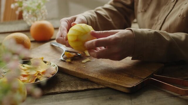 Female hands peeling fresh orange zest