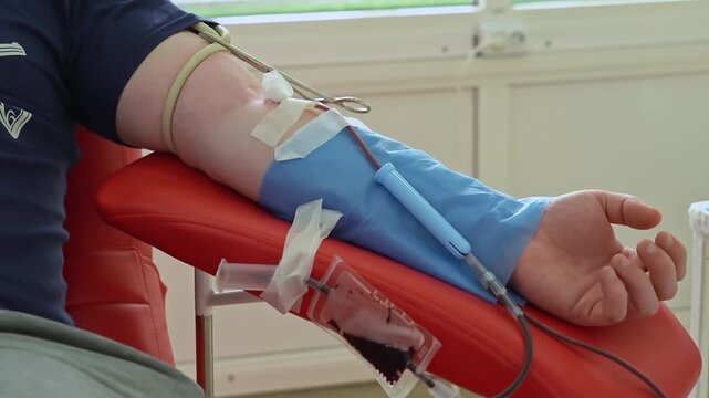 Close-up of donor arm with blood being collected into donation bag